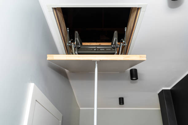 Folding metal stairs to the attic in the ceiling, closed hatch with a tube for opening, modern look. Folding metal stairs to the attic in the ceiling, closed hatch with a tube for opening, modern look. attic stock pictures, royalty-free photos & images