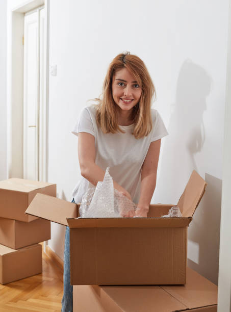 istock Cheerful girl unpacking cardboard boxes 1340466107
