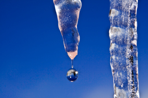 Water drops falling from thawing icicle.