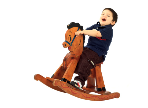 Three-year-old hispanic boy having fun on a vintage rocking horse.