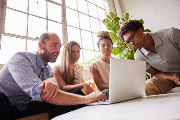 istock Diverse businesspeople smiling while working on a laptop in an office lounge 1340469480