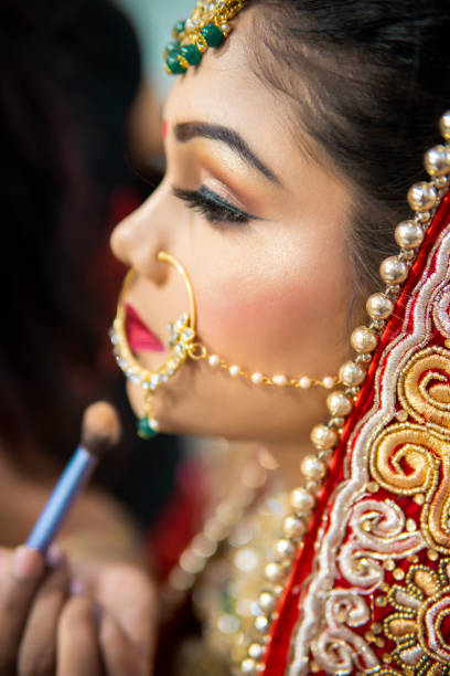 istock Beautiful traditional Indian bride getting ready for her wedding day by makeup. 1340470314