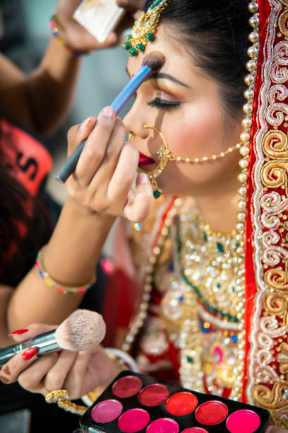 istock Beautiful traditional Indian bride getting ready for her wedding day by makeup. 1340470326