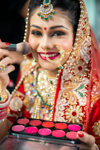 istock Beautiful traditional Indian bride getting ready for her wedding day by makeup. 1340470340