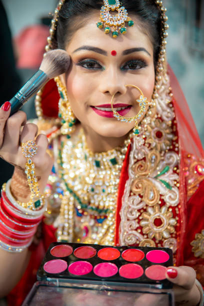 istock Beautiful traditional Indian bride getting ready for her wedding day by makeup. 1340470394