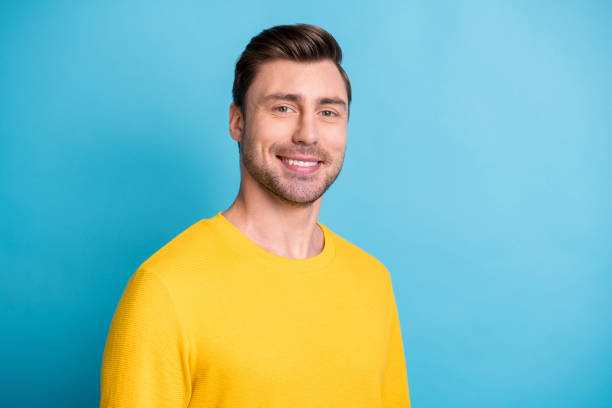 profile portrait of half turned young man smile look camera isolated on pastel blue color background - half smile imagens e fotografias de stock