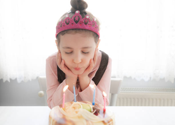 Happy girl making wish while blowing candles