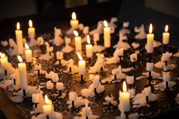 Candlestick with sacrificial candles Sacrificial candles on a large candlestick with many burned out candles and some still burning in a church candlemas stock pictures, royalty-free photos & images