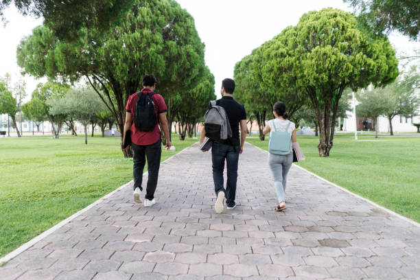 istock Back view of university students walking on campus with backpacks 1340480214