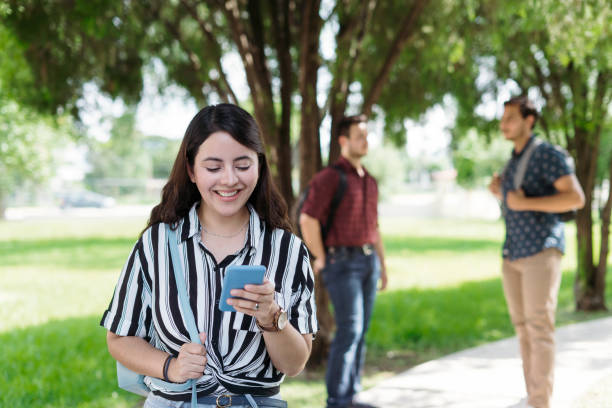 istock Pretty female student standing outside with phone and smiling 1340480333