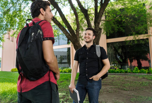 istock Two male students standing and talking outside 1340480558