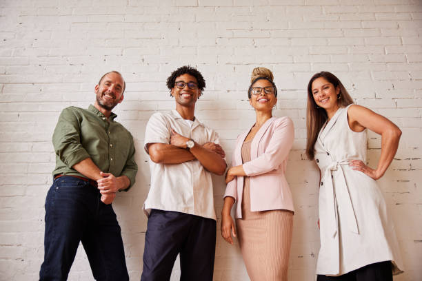 istock Group of diverse businesspeople smiling while leaning against a brick wall 1340482180