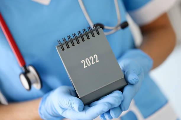 doctor in medical rubber gloves holding desk calendar for 2022 closeup - appointment reminder doctor calendar imagens e fotografias de stock