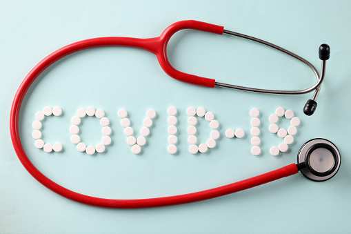 Red stethoscope lying near inscription from covid 19 tablets closeup. Diagnosis and treatment of covid19 pneumonia concept