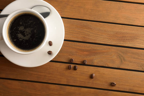 istock Cup with hot coffee on wooden slat table detail 1340486415
