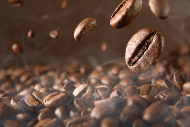 istock Roasted hot coffee beans falling on pile of coffee beans 1340486425