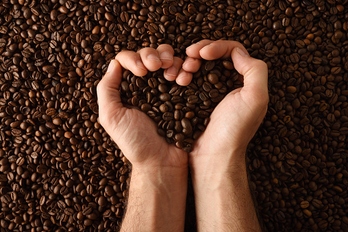 Background with heap of natural dry coffee beans close up. Top view. Horizontal composition.