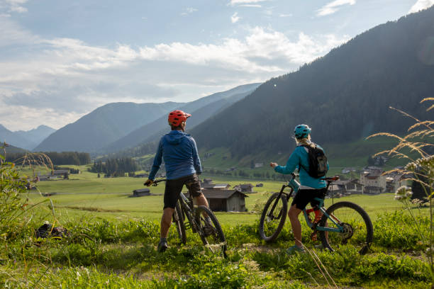 istock Mountain biking couple relax in grassy meadow 1340490097