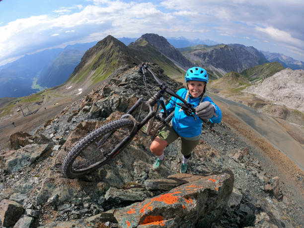 istock Female mountain biker hikes  up to mountain peak 1340490783