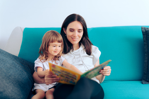 Happy mom and daughter looking in a picture book for children