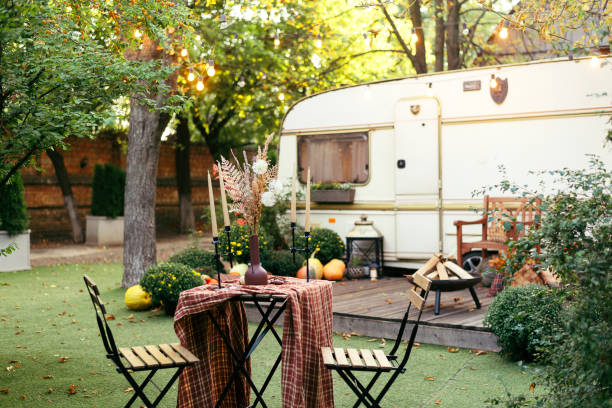 istock Autumn evening, romantic dinner in the garden. Table with tablecloth and decoration. Trailer with autumn decor and light bulbs 1340495191