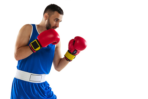Heavy fists. Championship preparation. Portrait of young male boxer standing training isolated over white background. Healthy lifestyle, sport, motion concept. Copy space for ad.