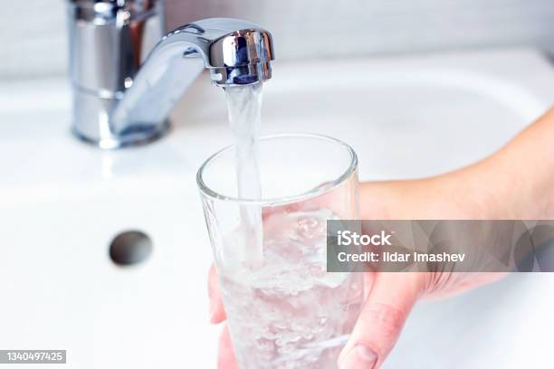 Young Caucasian Woman Hand Holding A Glass With Pure Drinking Water Pouring From Home Faucet Close Up Stock Photo - Download Image Now