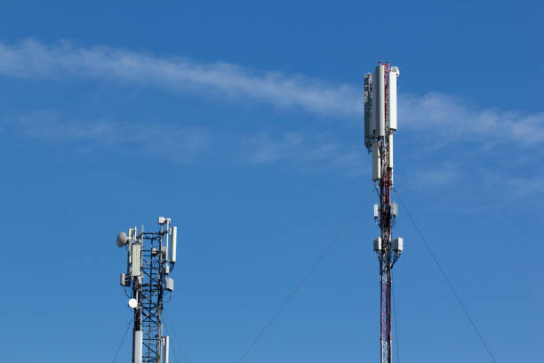 Mobile cell phone tower against the background of a blue sky and white cloud. Telecommunication TV tower. Cellular antenna. Wi-fi transmitter and receiver module.