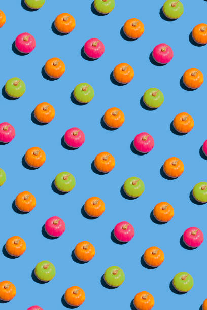 istock Creative 2021 Halloween pattern concept with orange, pink and green pumpkin against blue background. Minimal colorful decoration and craft concept, visual geometric arrangement. 1340499839