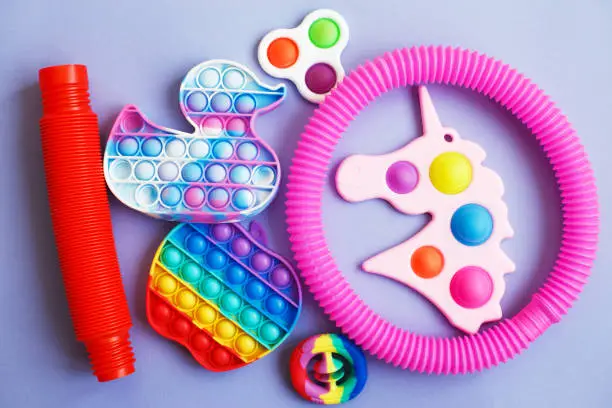 Photo of colorful antistress sensory fidget toys on a blue background.