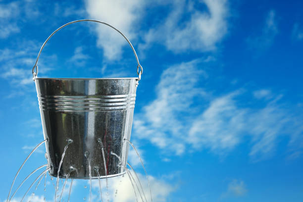 istock Leaky bucket with water against blue sky. Space for text 1340506939