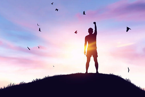 Man rising hands and birds flying on sunset sky at top of mountain field abstract background. Freedom feel good and travel adventure concept. Vintage tone filter effect color style.