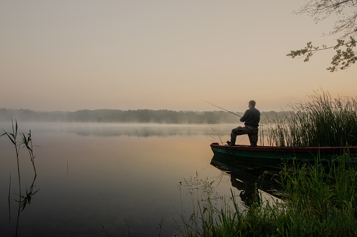 fisherman during foggy summer sunrise
