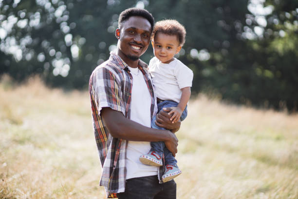 istock African man with son smiling and posing on camera outdoors 1340519603
