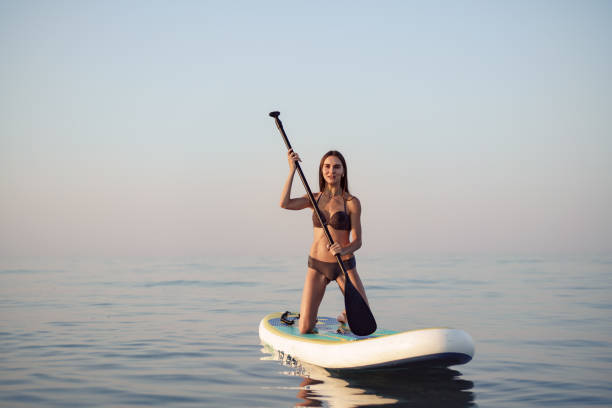 istock Young attractive woman standing on paddle board 1340520001