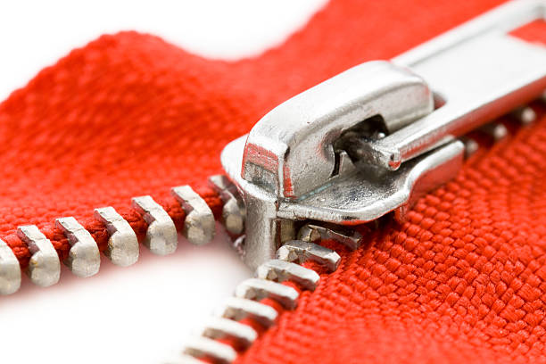 Extreme Close-up of a metallic zip closing (or opening) a red fabric.