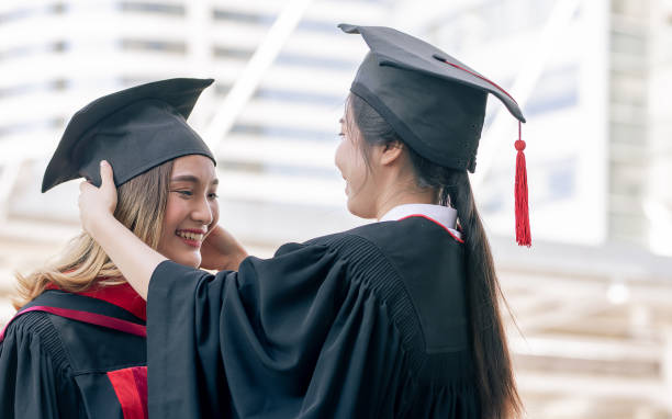istock Two asian female successful students dressing up, wearing uniform, cap and smiling with happiness after graduation. Education and Scholarship Concept. 1340521598