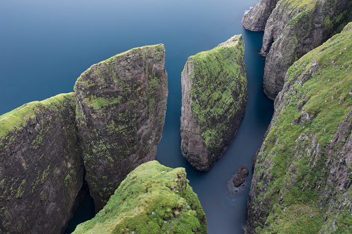 Amazing cliffs on the Faroe islands. A view of high peaks of mountains on a sunny day. Ocean view. 
Beautiful panoramic view. Northern Europe. Travel concept