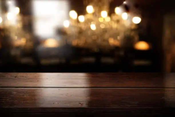Empty wooden bar counter with blurred restaurant interior and elegant bokeh. Background for gastronomy and cafe.