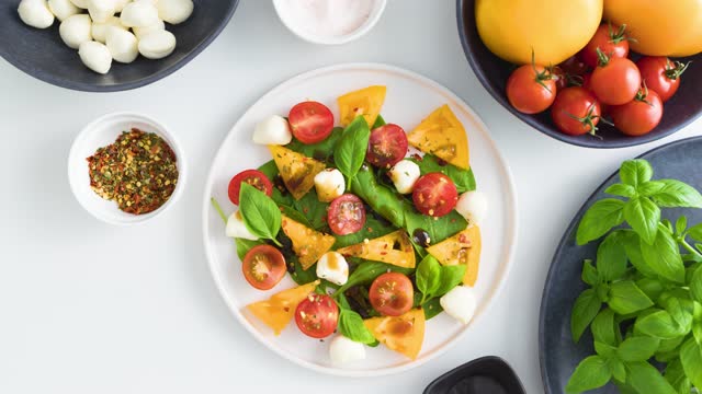 Italian caprese salad with tomatoes, mozzarella cheese and basil in plate - Stop Motion Animation