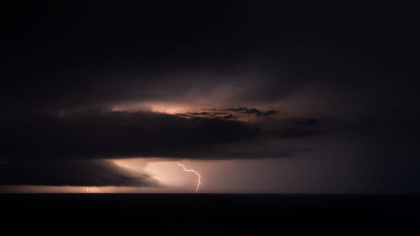 istock Distant lightning and dark storm clouds over the sea, panoramic. 1340535601