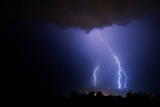 istock Three powerful lightning bolts during a night thunderstorm over the sea. 1340535659