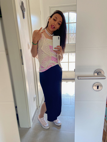Woman takes a selfie with her  summer outfitt before living the house.