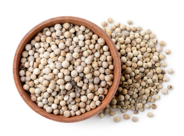 istock Dry white peppercorns in a plate on a white background, isolated. Top view 1340542117