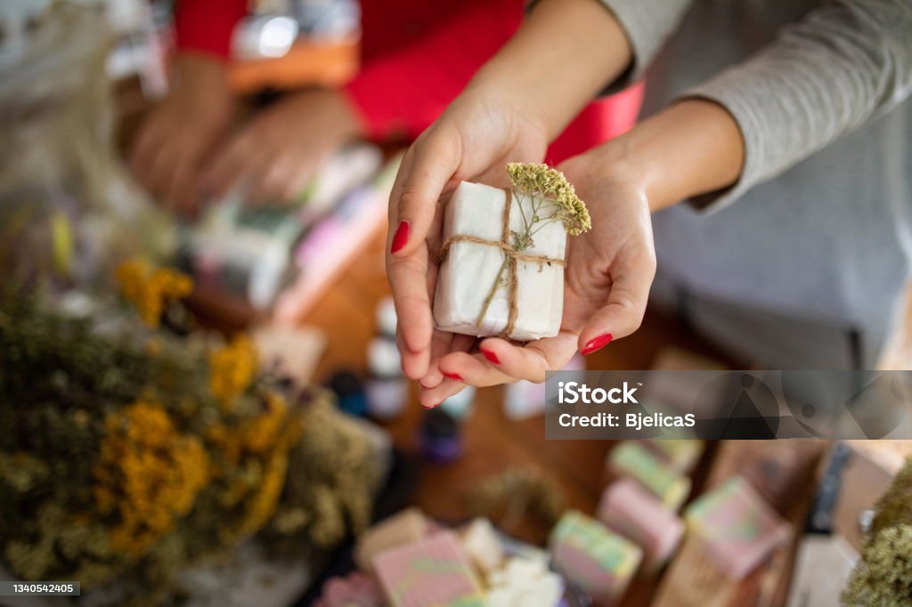 Young woman holding packed handmade soaps from natural oils at her home workshop Soap Stock Photo
