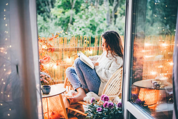 donna che si rilassa su un comodo balcone, leggendo un libro. - balcony house golf home interior foto e immagini stock