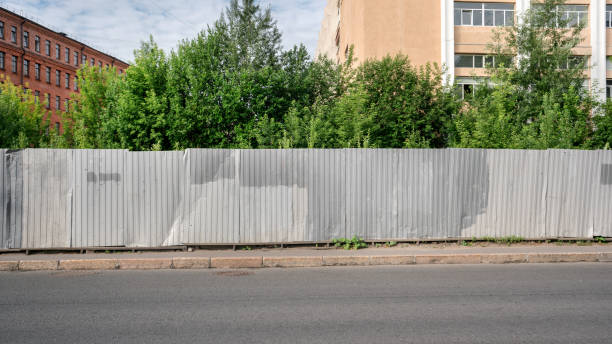 istock Worn metal long grey colored fence on sidewalk along asphalt road 1340550170