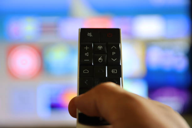 istock Image of unrecognisable person's hand holding a TV remote control, pointing at television screen, changing channels from rows of Smart Television Screen App Icons, background 1340551910