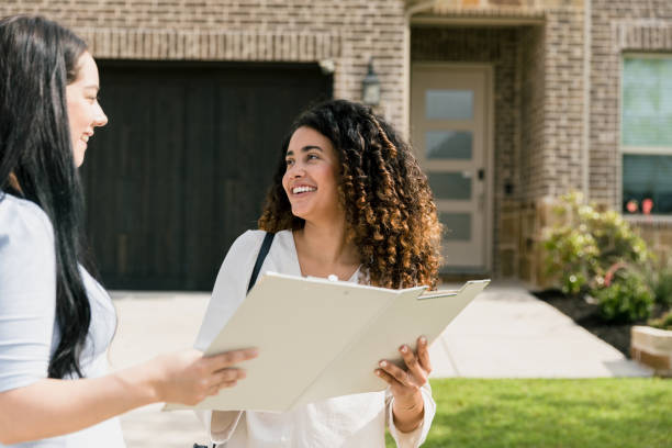 istock Woman smiles at real estate agent while looking at paperwork 1340553906