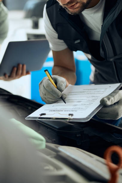 istock Close up of mechanic taking notes while analyzing car engine with his coworker in a workshop. 1340556182